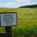 Wooden sign in a green agricultural field with text about selecting the right sprayer pump for Latin American crop protection.